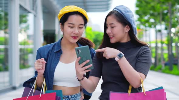 Smiling young Asian woman with shopping colour bags over mall alt