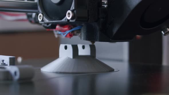 Close Up of an 3d printing process. The 3d printer prints with an grey filament. The object is almos alt