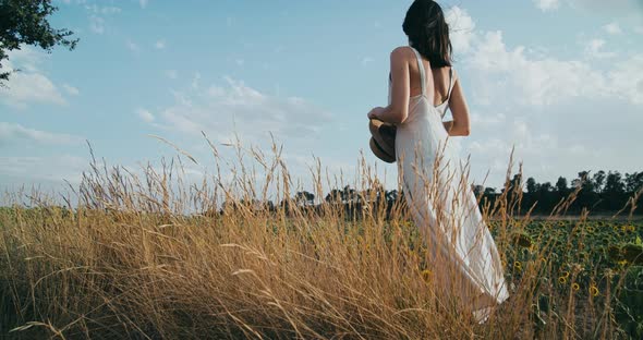 Back View Woman Stands on Agricultural Field in Dress Enjoying Beautiful View alt