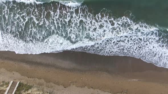 View of the Sea Surf on a Sandy Beach with a Wooden Ladder To the Water