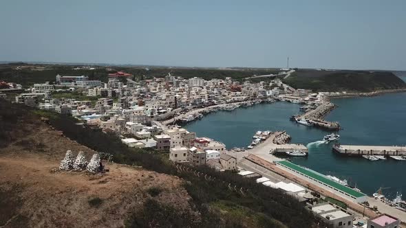 Drone shot of a sea harbour with city buildings in penghu island located in Taiwan alt
