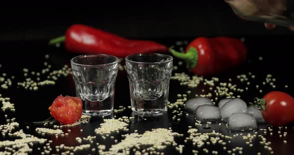 Pour Vodka Into Shot Glasses Placed on a Black Surface alt