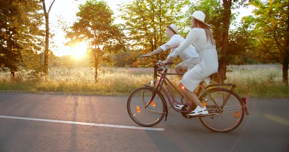 Couple Riding Bicycles on Countryside Road Sunset