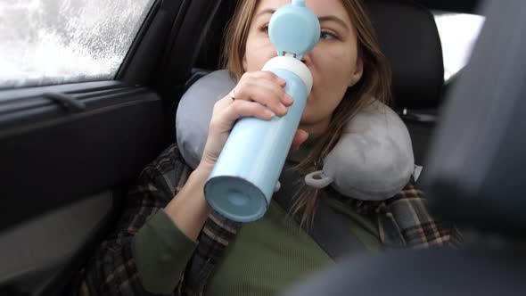 Thermos in the Hands of a Woman in the Car in Winter