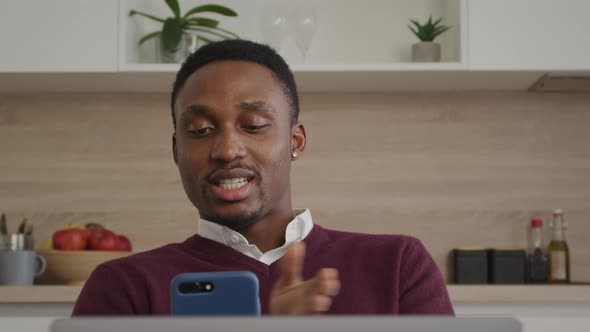 Happy Smiling African American Man Greeting His Friends on a Video Call on a Laptop at Home Interior alt