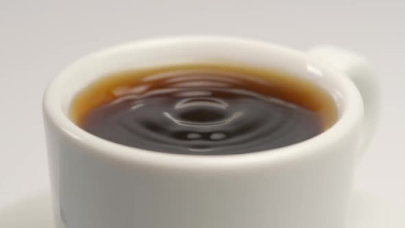 Falling of coffee drop to a white cup