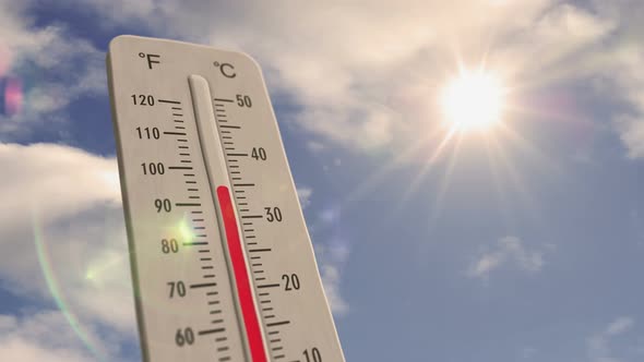 Thermometer on blue sky and shining sun