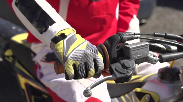 A young man gripping the throttle to rev up his motocross dirt motorcycle. alt