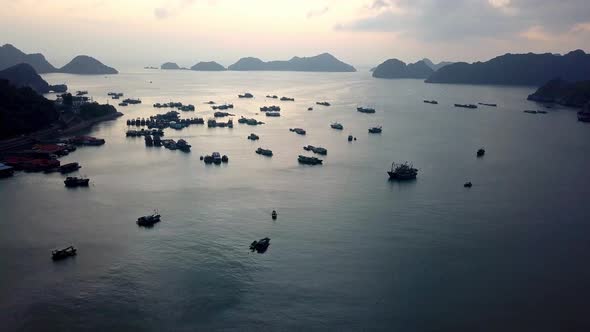 Port of Ha Long Bay Vietnam during sundown with dozens of commercial ships, Aerial flyover shot alt