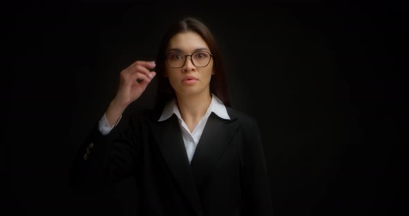 Shocked Businesswoman Raises Her Glasses in Surprise Against Black Background