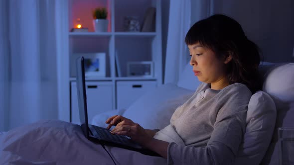 Woman with Laptop in Bed at Home at Night alt