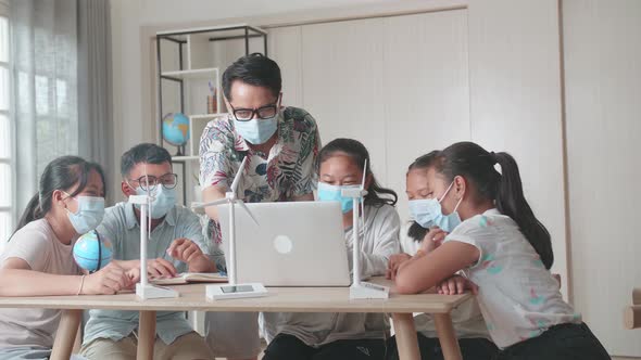 Enthusiastic Asian Teacher Explains To Young Children How Wind Turbines Work. Renewable Energy alt