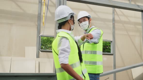 Asian workers people wearing face mask on site and make elbow bump in architecture due to covid 19. alt