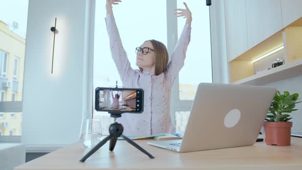 Young woman freelancer, blogger, online live broadcast. Tired yawns and stretches alt