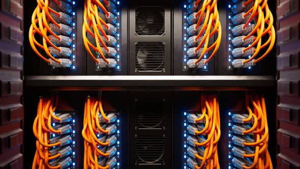 Countless orange cables in a  server cabinet lit by a single spotlight. 4KHD alt