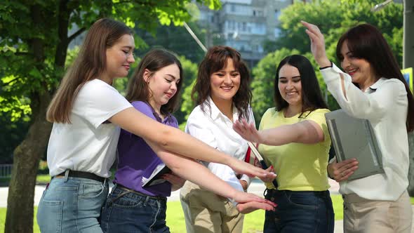 Multicultural Friends Stand in Circle Placing Their Raised Hands Together Centre alt