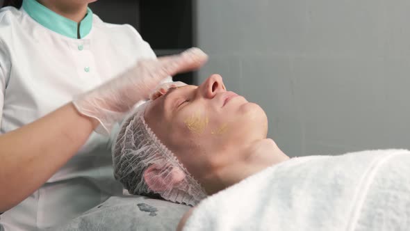 A Cosmetologist Gives a Facial Massage to a Young Man