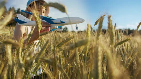 Funny Boy in a Hat Playing with Airplane in Wheat Field, Boy Dreams of Being a Pilot