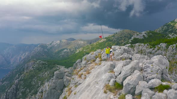 Young Travelers Standing on a Mountain Peak and Looking on Sea of Kotor Bay Montenegro alt