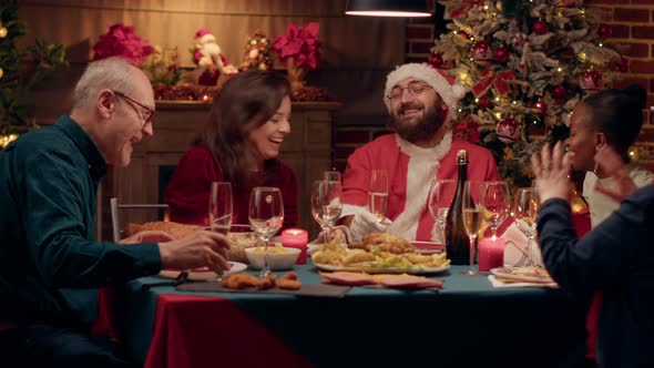 Funny Person Costumed As Santa Claus Conversating with Family About Gifts While Enjoying Christmas alt