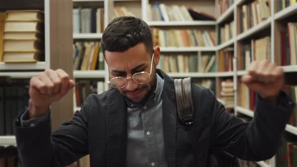 Happy Man Dancing in Library Among Bookcases