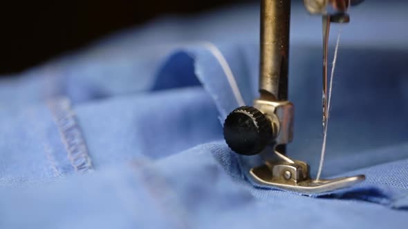 Sewing Machine Sews Blue Fabric With White Thread