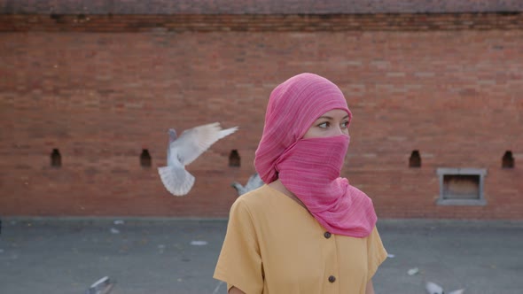 Attractive Muslim Woman with Natural Make Up Wearing Pink Hijab Scarf Looks at Camera alt