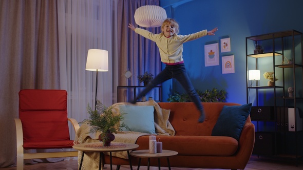 Active Funny Girl Kid Jumping Dancing Fooling on Soft Cozy Sofa at Home Spend Free Time Alone alt