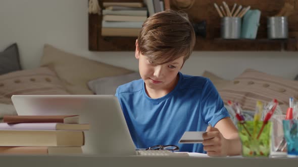 online shopping with credit card, student boy uses a computer at home, surfs the internet