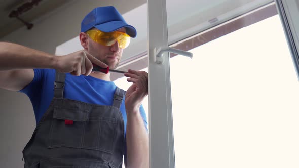 Man in Goggles Fixes Flat Window Handle with Screwdriver alt