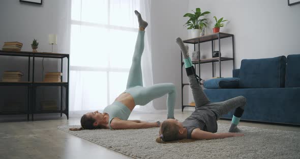 Little Preschool Girl and Her Mother Are Doing Sport Activity at Home Lying on Carpet in Room alt