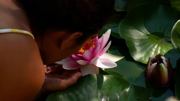 Beautiful girl leans towards the lotus flower. Lotus flower in a pond pink close-up. alt