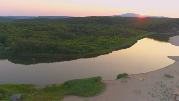 Aerial View of Red Sunset Over Mountains, Green Forests and Veleka River Mouth Flowing in To the Sea alt