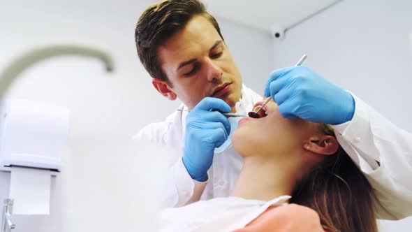Dentist examining a female patient with tools alt