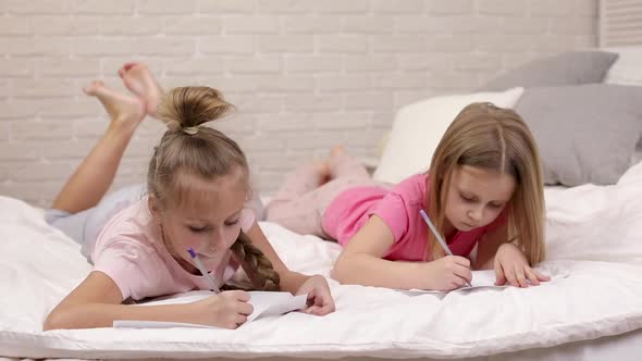 Kids Drawing Pictures While Lying on Bed