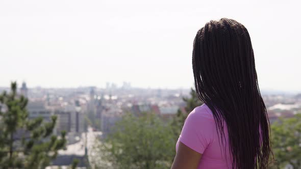 A Young Black Woman Looks at a Blurry Cityscape alt