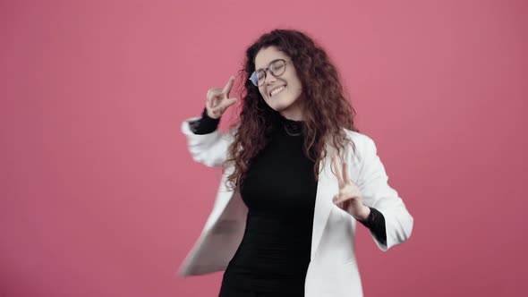 The Happy Young Woman with Curly Hair Dances with Her Hands Two Open Fingers Fluttering alt