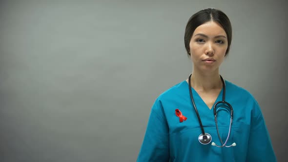 Asian Female Doctor With Red Ribbon, International HIV AIDS Awareness Sign alt