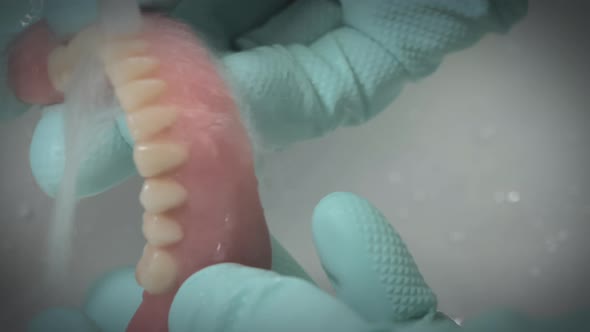 Closeup Shot of Dentures Being Cleaned Under Running Water