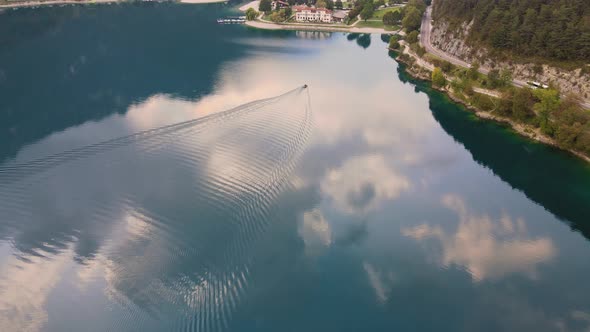 Drone goes down following a little boat on Ledro lake, Trentino, Val di Ledro in North Italy. Aerial alt