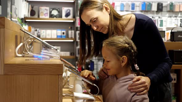 Mother with Daughter Choosing a Smartphone in an Electronics Store