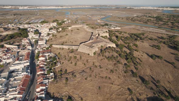 Hilltop Castro Marim Castle, fortress overlooking town and salt plans. Aerial forward alt