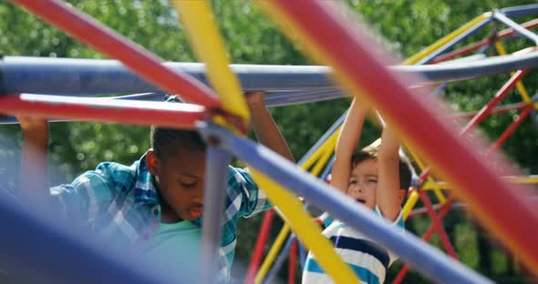 Schoolkids playing on monkey bar in playground alt