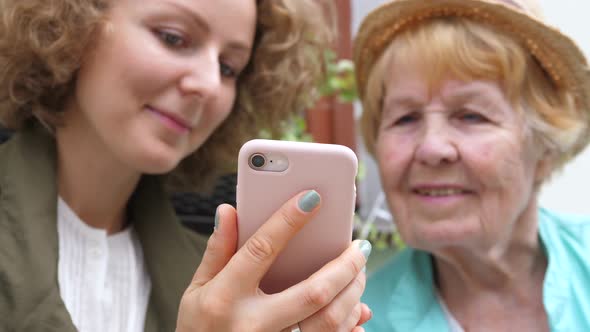 Granddaughter Teaching Grandma How To Use Smartphone alt