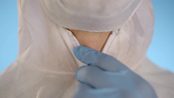 Closeup of Man in Medical Mask Blue Rubber Gloves Zips Up on Protective Suit