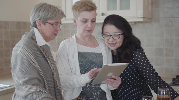 Three Mature Girlfriends Are Watching Something Interesting on the Tablet and Are Actively alt