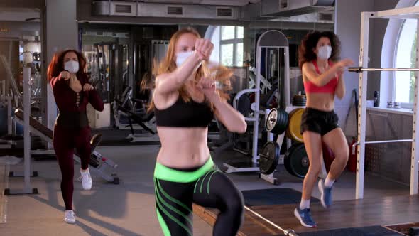 Group of Young Beautiful Female Athletes Wearing Face Masks Doing Boxing Warm-up Aerobics in the Gym