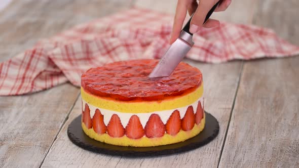 Cutting Fresh Baked Cake with Strawberry Jelly Topping