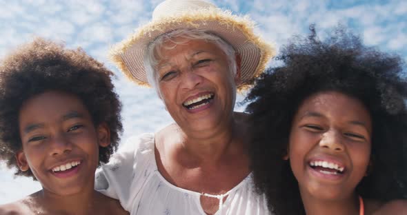 Portrait of mixed race senior woman with grandchildren smiling at the beach alt