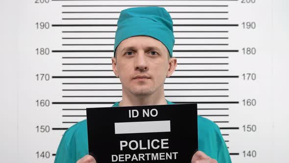 Mugshot of a Surgeon in Green Clothes, at the Police Station alt